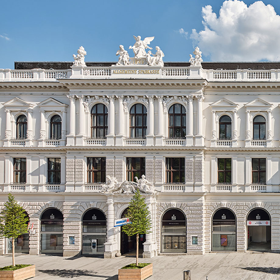 Filiale der Sparkasse in klassizistisches Gebäude mit dekorativer Fassade und Figuren auf dem Dach.